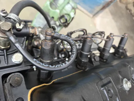 Vier Düsenhalter mit Rücklaufleitung auf dem Zylinderkopf eines Multicar M25 Dieselmotors